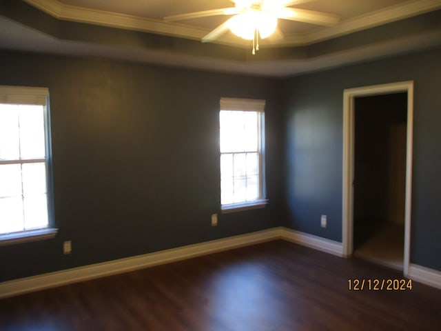 unfurnished room featuring a tray ceiling, crown molding, ceiling fan, and dark hardwood / wood-style floors