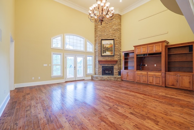 unfurnished living room with french doors, a high ceiling, crown molding, a chandelier, and hardwood / wood-style flooring