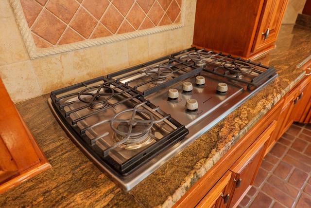 details featuring tasteful backsplash, stainless steel gas cooktop, and dark stone counters