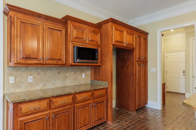 kitchen featuring decorative backsplash, light stone counters, and crown molding