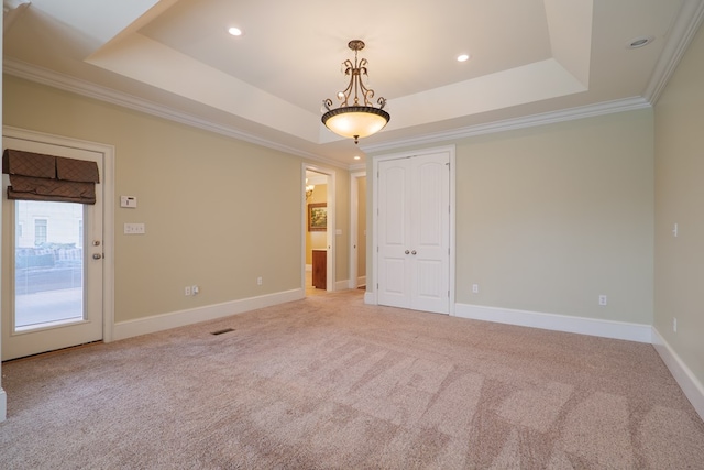 empty room featuring light carpet, a raised ceiling, and ornamental molding