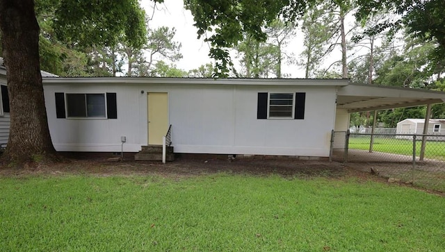 rear view of house featuring a carport and a yard