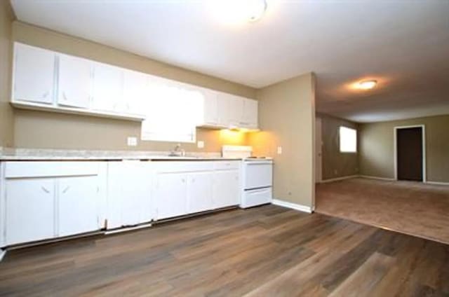 kitchen with stove, sink, white cabinets, and dark hardwood / wood-style flooring