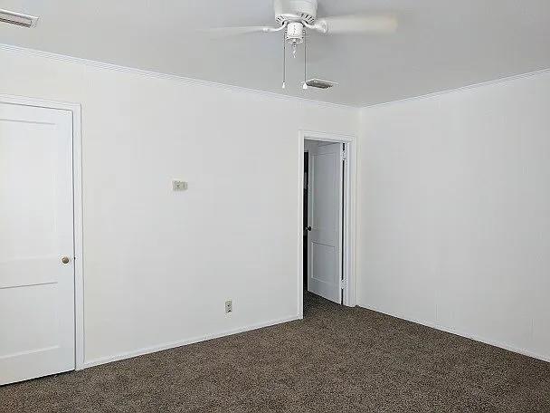 spare room featuring dark colored carpet and ceiling fan