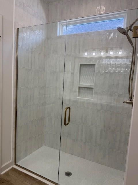 bathroom with hardwood / wood-style floors and a shower with shower door