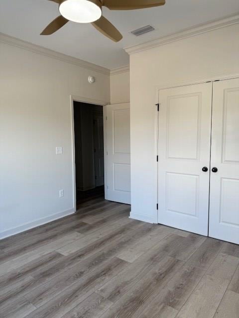 unfurnished bedroom featuring ornamental molding, a closet, ceiling fan, and light wood-type flooring