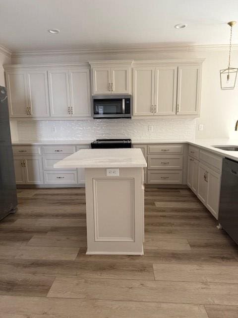 kitchen featuring hanging light fixtures, sink, white cabinets, and appliances with stainless steel finishes