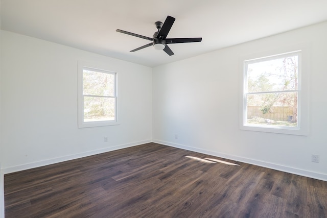 spare room featuring ceiling fan, dark wood-type flooring, and baseboards