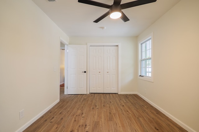 unfurnished bedroom with ceiling fan, a closet, and wood-type flooring