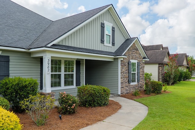 3982 Karaline Cir, Valdosta, GA 31605 - view of front of home with board and batten siding, stone siding, a front yard, covered porch, and roof with shingles