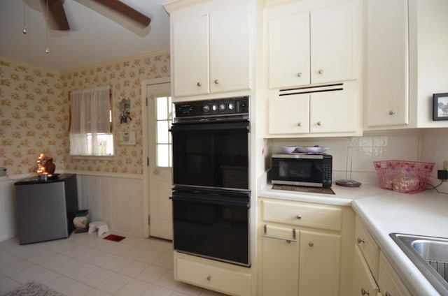 kitchen featuring stainless steel microwave, wallpapered walls, light countertops, wainscoting, and dobule oven black