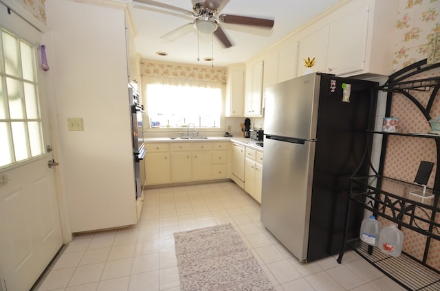 kitchen with wallpapered walls, dishwasher, freestanding refrigerator, a ceiling fan, and a sink