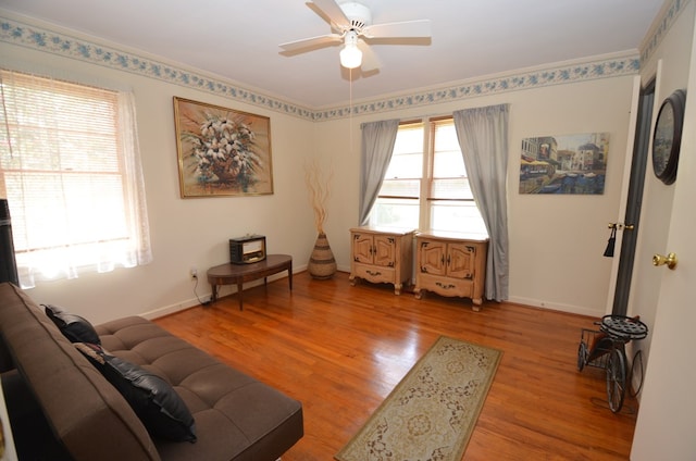 living area featuring baseboards, light wood-type flooring, and ceiling fan