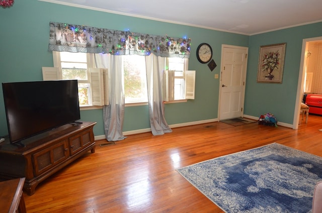 living room with visible vents, baseboards, wood finished floors, and ornamental molding