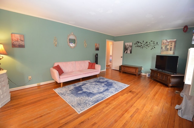 living area with baseboards, wood finished floors, and crown molding