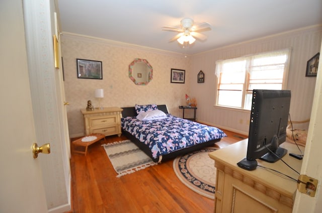 bedroom with ornamental molding, wallpapered walls, baseboards, and wood finished floors