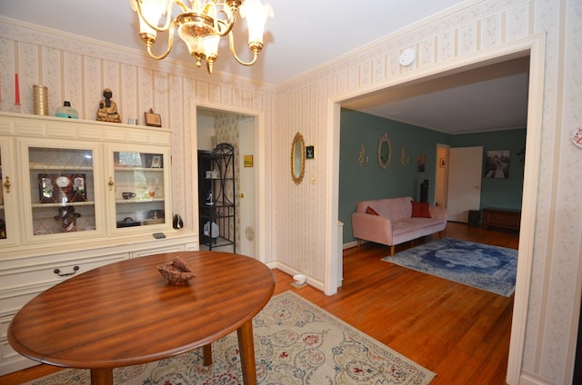 dining space with ornamental molding, light wood-style floors, wallpapered walls, baseboards, and a chandelier