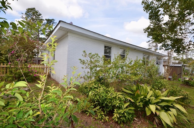 view of side of property featuring brick siding and fence