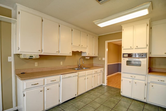 kitchen with white cabinetry, sink, light tile patterned flooring, and white appliances