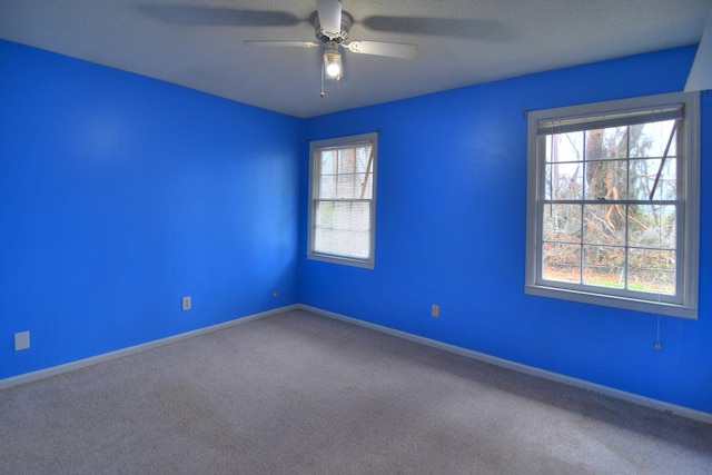 carpeted spare room featuring ceiling fan