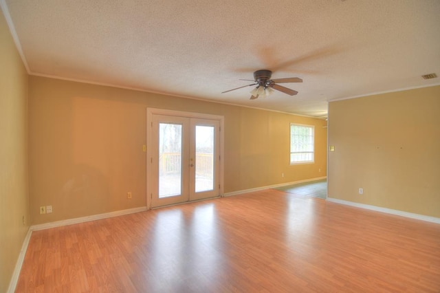 empty room featuring french doors, crown molding, ceiling fan, light wood-type flooring, and a textured ceiling