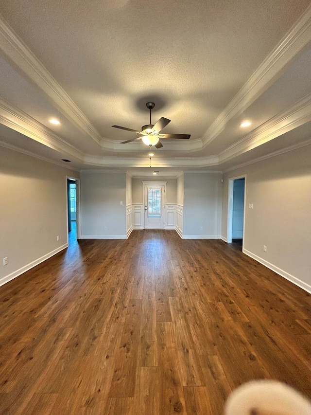 spare room featuring a tray ceiling, crown molding, and dark wood-type flooring