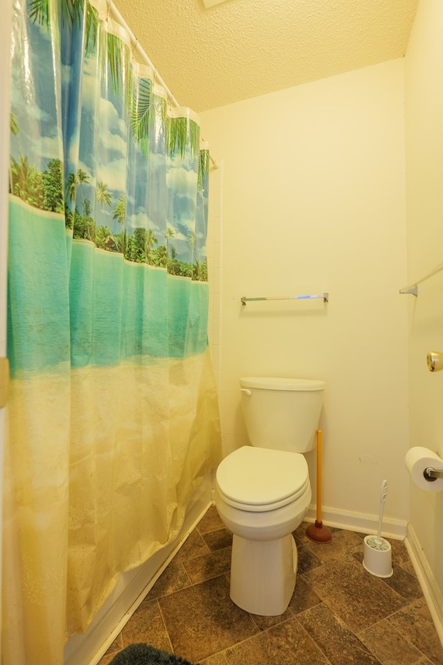 bathroom with baseboards, a textured ceiling, and toilet