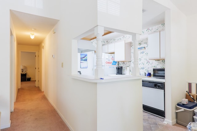 kitchen featuring white appliances, light countertops, white cabinetry, a peninsula, and a towering ceiling