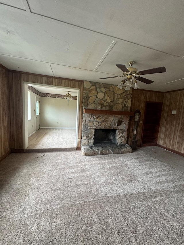 unfurnished living room with wood walls, light colored carpet, and a fireplace