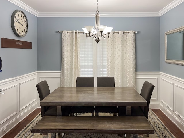 dining room with a decorative wall, ornamental molding, an inviting chandelier, and wood finished floors