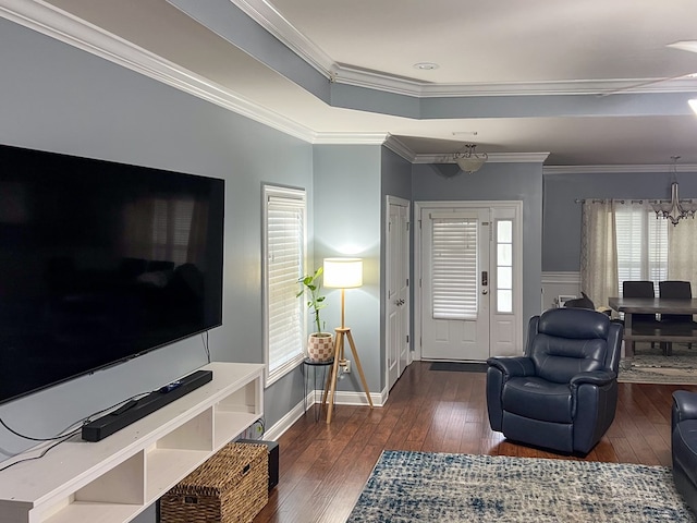 living room with baseboards, a chandelier, a tray ceiling, ornamental molding, and wood-type flooring