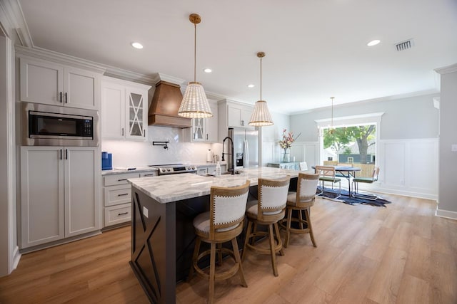 5039 Hatfield Cir, Hahira, GA 31632 - kitchen with stainless steel appliances, custom exhaust hood, a decorative wall, a kitchen island with sink, and a sink
