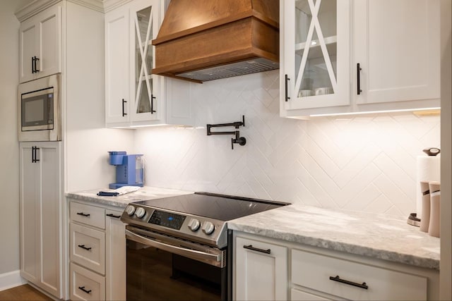 5039 Hatfield Cir, Hahira, GA 31632 - kitchen featuring appliances with stainless steel finishes, custom exhaust hood, decorative backsplash, and white cabinets