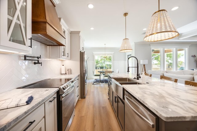 5039 Hatfield Cir, Hahira, GA 31632 - kitchen featuring appliances with stainless steel finishes, custom exhaust hood, a sink, light wood-style floors, and glass insert cabinets
