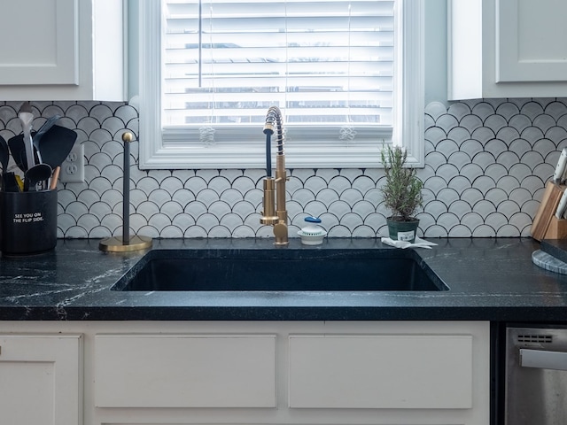 room details with white cabinetry, backsplash, stainless steel dishwasher, and sink