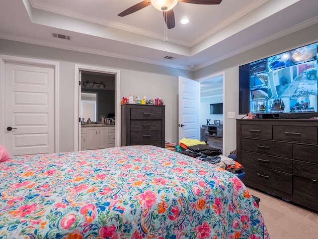 carpeted bedroom with ceiling fan, ornamental molding, a raised ceiling, and ensuite bath