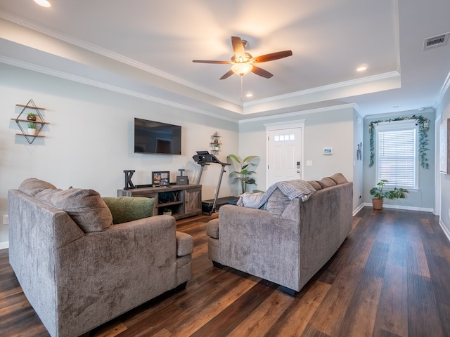 living room with crown molding, a tray ceiling, and dark wood-type flooring