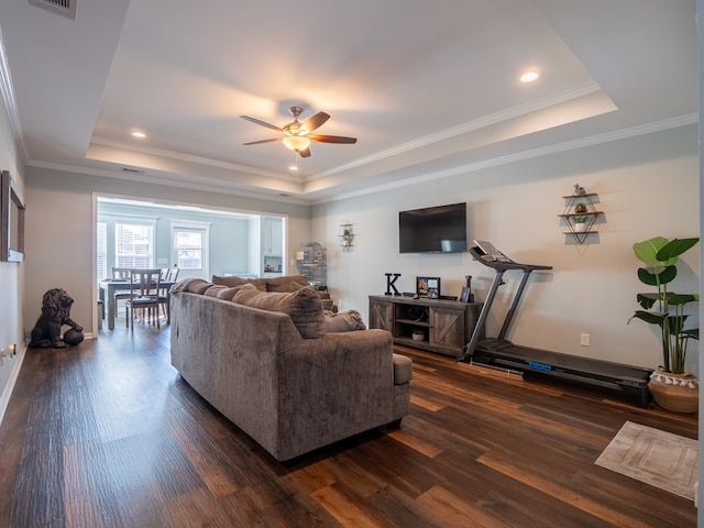 living room with dark hardwood / wood-style floors, ornamental molding, and a tray ceiling