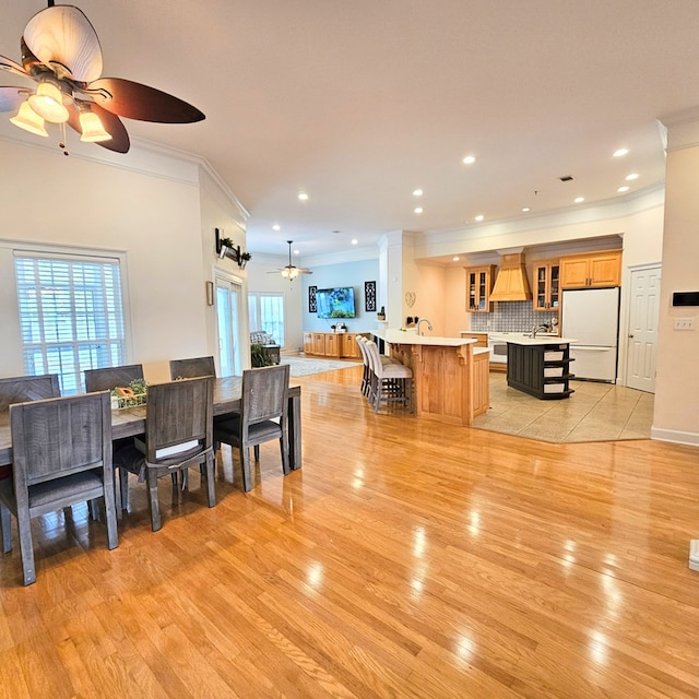 dining area with crown molding, ceiling fan, and light wood-type flooring