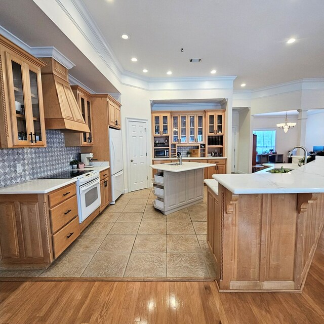 interior space featuring ornate columns, ornamental molding, a notable chandelier, and light hardwood / wood-style flooring