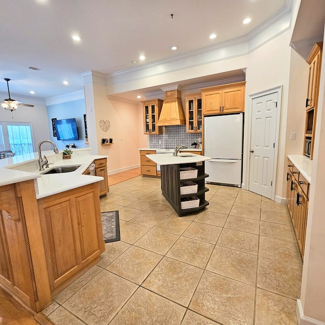 kitchen with white fridge, sink, a center island with sink, and backsplash