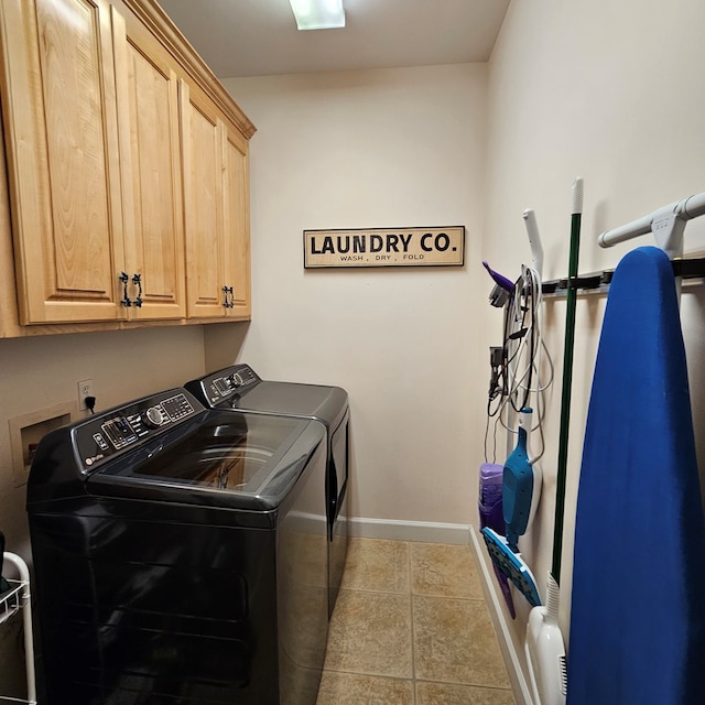 clothes washing area with cabinets, washing machine and dryer, and light tile patterned flooring