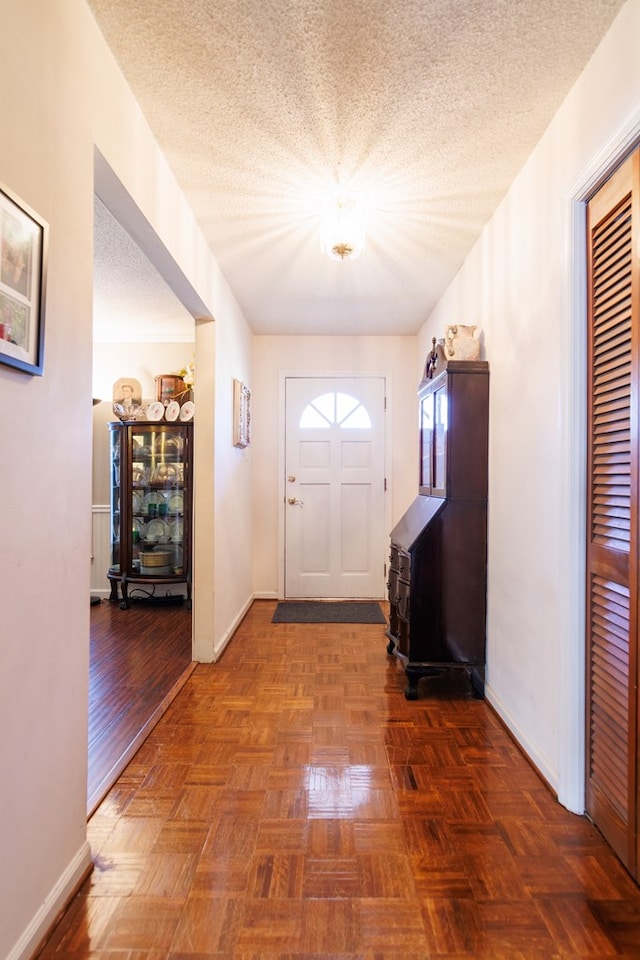 doorway with baseboards and a textured ceiling