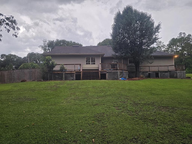 rear view of house featuring a lawn and a wooden deck