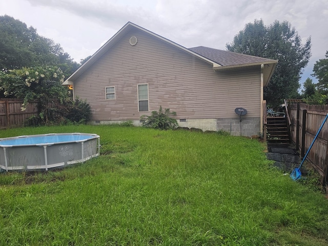 view of home's exterior featuring a lawn and a fenced in pool