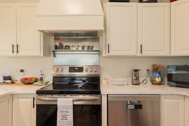 kitchen with white cabinets, light stone counters, premium range hood, and stainless steel appliances