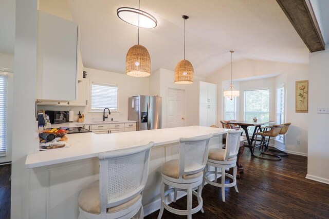 kitchen featuring kitchen peninsula, a breakfast bar, stainless steel fridge, and plenty of natural light