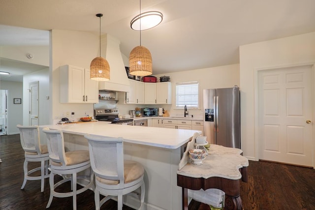 kitchen featuring dark hardwood / wood-style flooring, stainless steel appliances, vaulted ceiling, white cabinetry, and hanging light fixtures