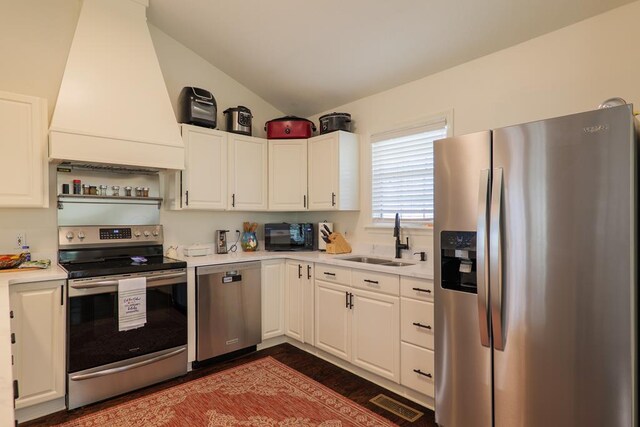 kitchen featuring white cabinetry, sink, lofted ceiling, appliances with stainless steel finishes, and custom exhaust hood