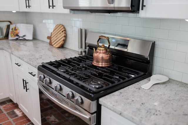 kitchen featuring light stone countertops, decorative backsplash, white cabinets, and stainless steel appliances